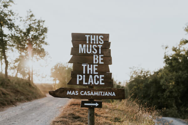 Wooden roadside sign reading This Must Be The Place, Mas Casamitjana